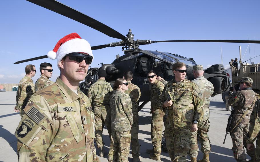 Spc. Adam Wells, 25, an armament soldier with the 4th Battalion (Attack Reconnaissance), 4th Aviation Regiment, watches as celebrities inspect his AH-64 Apache attack helicopter at a Christmas event with the USO on Dec. 24, 2018, at Camp Dahlke West in Afghanistan. 