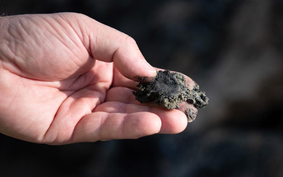 David Brown, a forensic archaeologist for the Defense POW/MIA Accounting Agency, holds soil Oct. 30, 2023, in Wistedt, Germany, that he says was blackened in a past air crash.