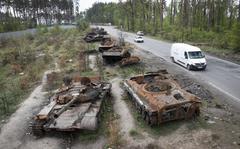 FILE - Cars pass by destroyed Russian tanks in a recent battle against Ukrainians in the village of Dmytrivka, close to Kyiv, Ukraine, May 23, 2022. Three months after it invaded Ukraine hoping to overtake the country in a blitz, Russia has bogged down in what increasingly looks like a war of attrition with no end in sight. (AP Photo/Efrem Lukatsky, File)