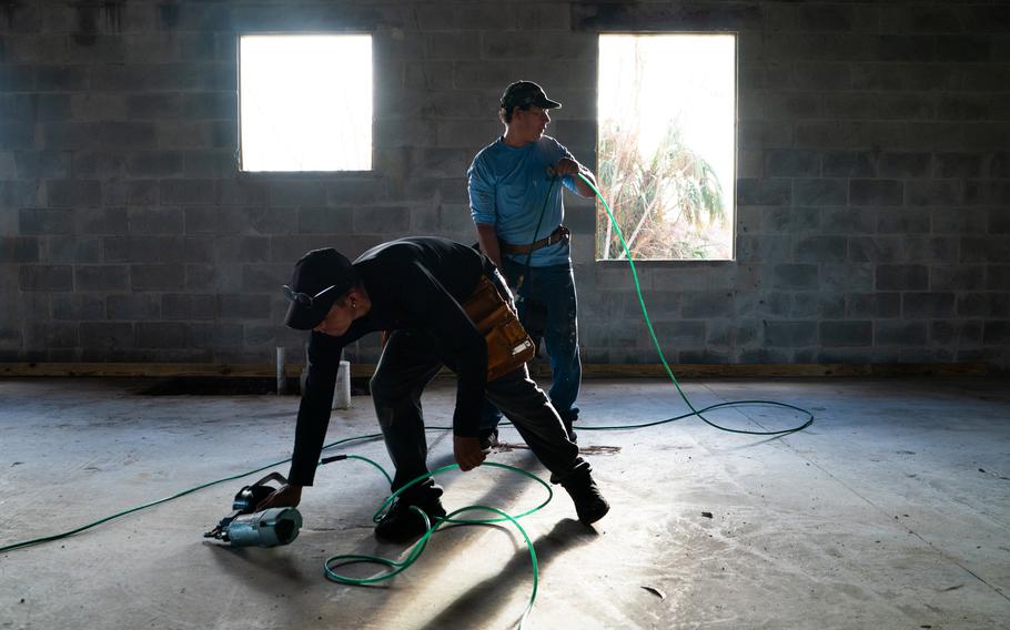 Honduras immigrant Pedro Carias, 37, right, uses a nail gun at a job site in Fort Meyers. 