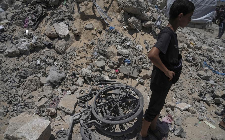 A boy stands with his hands on his hips, surrounded by rubble.