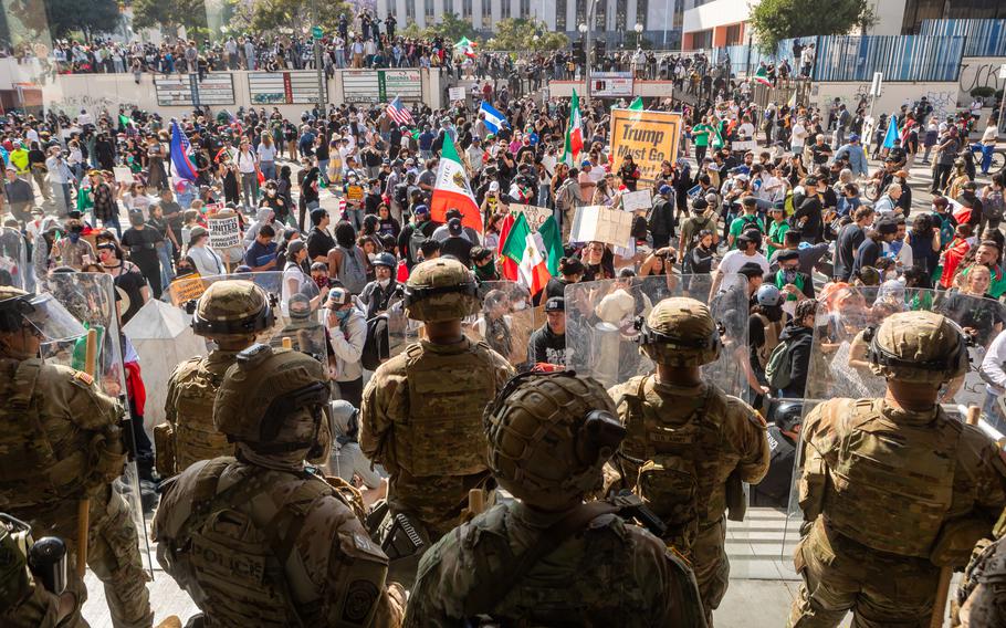National Guard troops stand by during protests in Los Angeles. Protesters wave Mexican as well as U.S. flags.