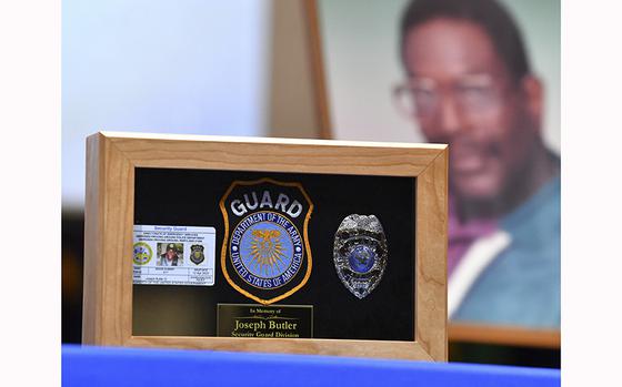A small shadow box containing the badge, patch and ID card for APG Security Officer Joseph Butler sits on the stage with photos and other items during the memorial servicehonoring Butler at the Aberdeen Proving Ground Post Theater Thursday, May 5, 2023. Butler was a beloved security officer at Aberdeen Proving Ground for over 20 years.