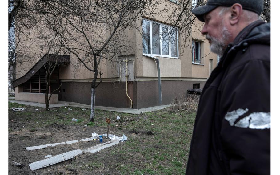 Oleg Yevtushenko, 55, stands by the grave of his neighbor he said was killed by Russian soldiers in Bucha, Ukraine. 