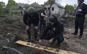 A Ukrainian police officer and war crime prosecutor inspect fragments of a glide bomb in front of damaged house, after a Russian airstrike on a residential neighbourhood in Kharkiv, Ukraine, Saturday, May 18, 2024. (AP Photo/Evgeniy Maloletka)