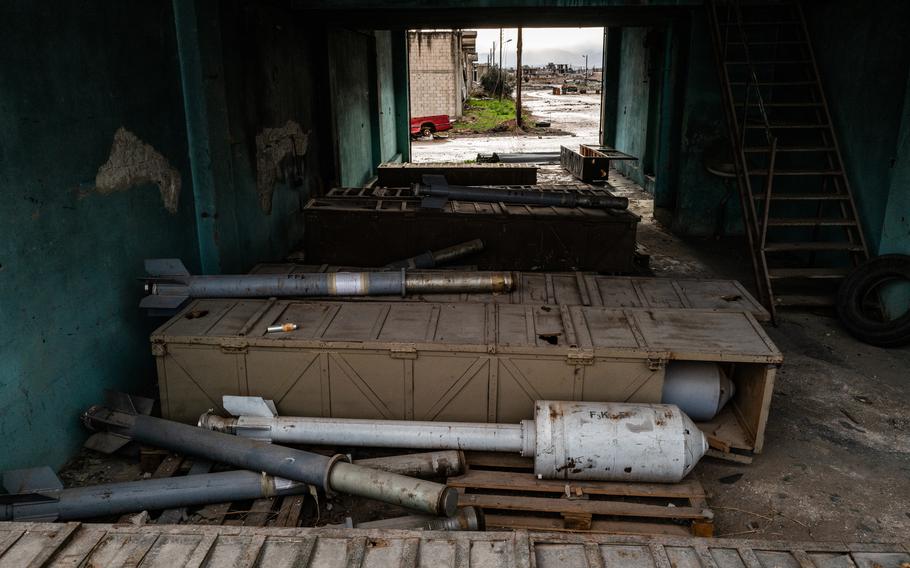 A wooden crate is seen in a storage facility with some missile components/heads next to it.