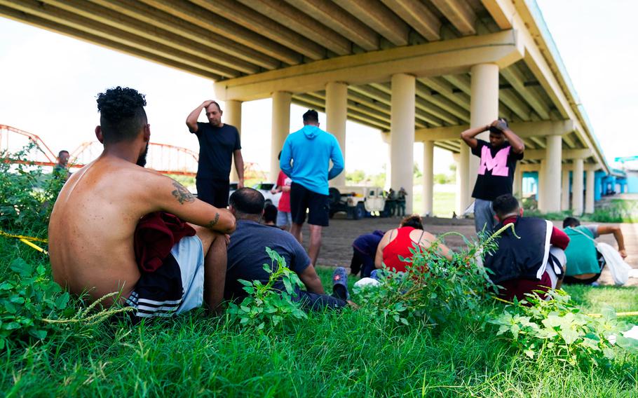 Migrants wait to be processed by the Border Patrol after illegally crossing the Rio Grande River from Mexico into the United States at Eagle Pass, Texas, Friday.