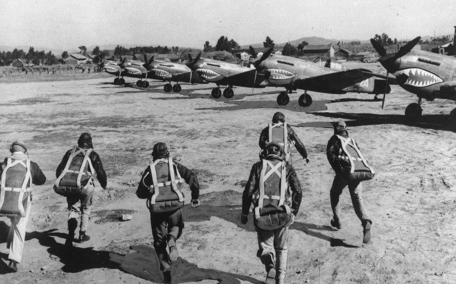 American pursuit pilots of the famed Flying Tigers run for their Curtiss P-40 fighters as an air raid warning sounds, at an unknown airbase in China, on November 2, 1943. 
