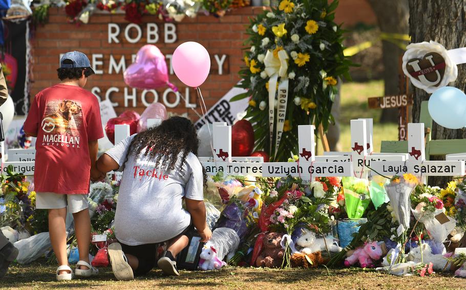 Family members place a picture at a memorial outside Robb Elementary School in Uvalde, Texas, where 19 students and two teachers died when a gunman opened fire in a classroom.