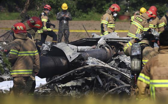 Emergency personnel surround a pile of wreckage.