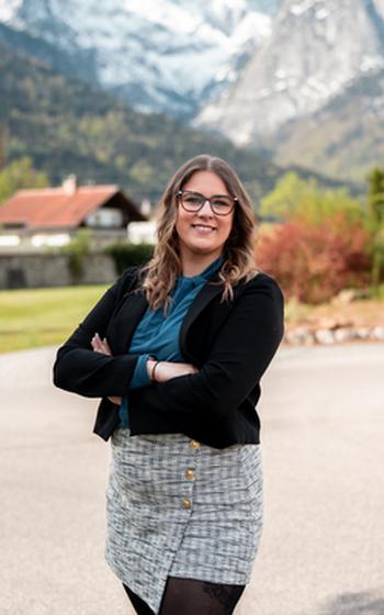 Hailey Smart standing in front of a house a snow-capped mountain