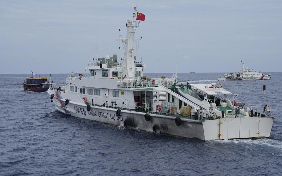 A Chinese coast guard ship tries to block the way of a Philippine supply boat, left, as it heads toward Second Thomas Shoal, locally known as Ayungin Shoal, at the disputed South China Sea on Aug. 22, 2023. Philippine officials on Monday, Sept. 25 condemned a floating barrier laid by Chinese coast guard vessels to prevent Filipino fishermen from entering a disputed lagoon in the South China Sea and took action to remove the obstruction. 