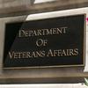 A plaque reads “Department of Veterans Affairs” on the side of a building next to a red flower.