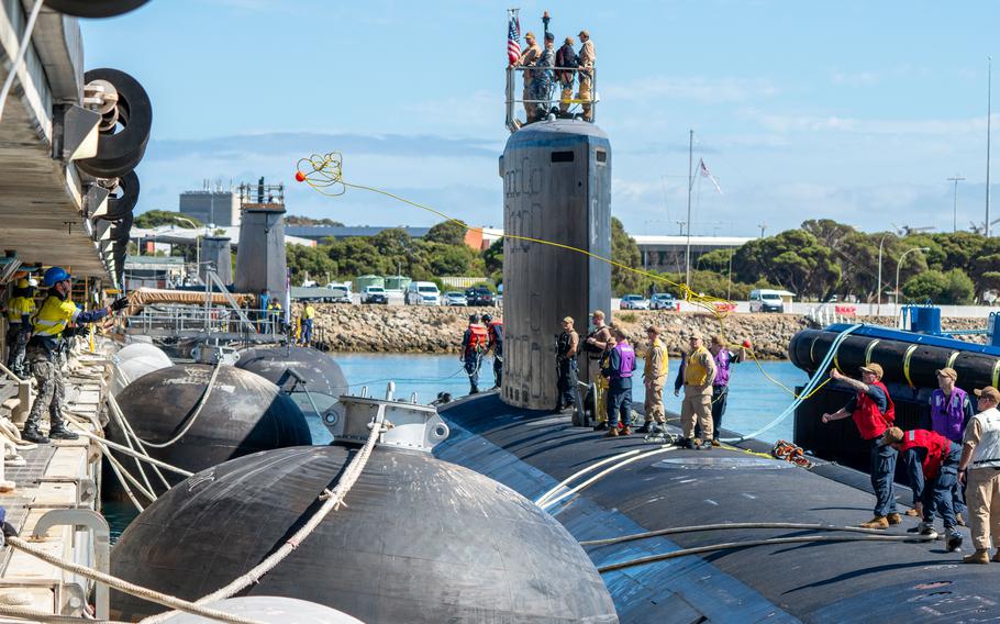 Sailors on the deck of a submarine as the ship is moored.