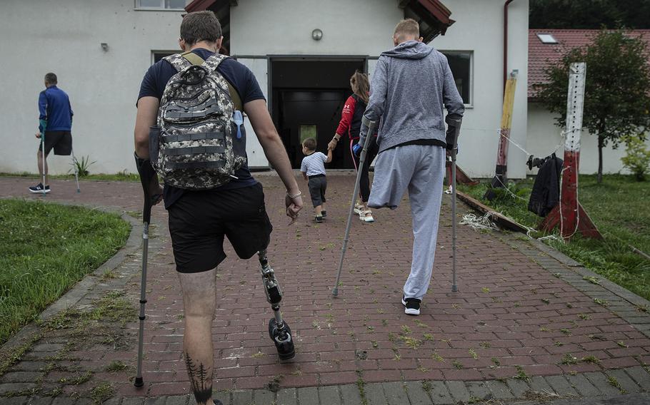 Injured Ukrainian soldiers Serheii, 26, left, and Demitri, 34, far left, and Dimitro, 36, arrive at the horse farm on July 31, 2022.