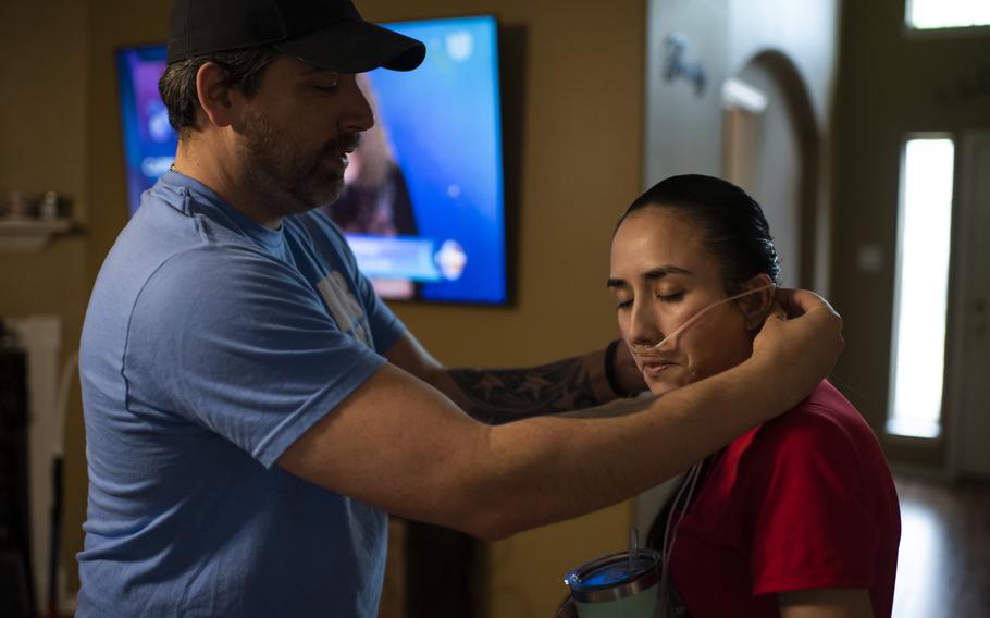 Chris Crouch helps his wife, Diana, put on an oxygen tube at home. 