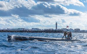 Marines operate a vessel with a low-profile deck that is nearly parallel with the water.