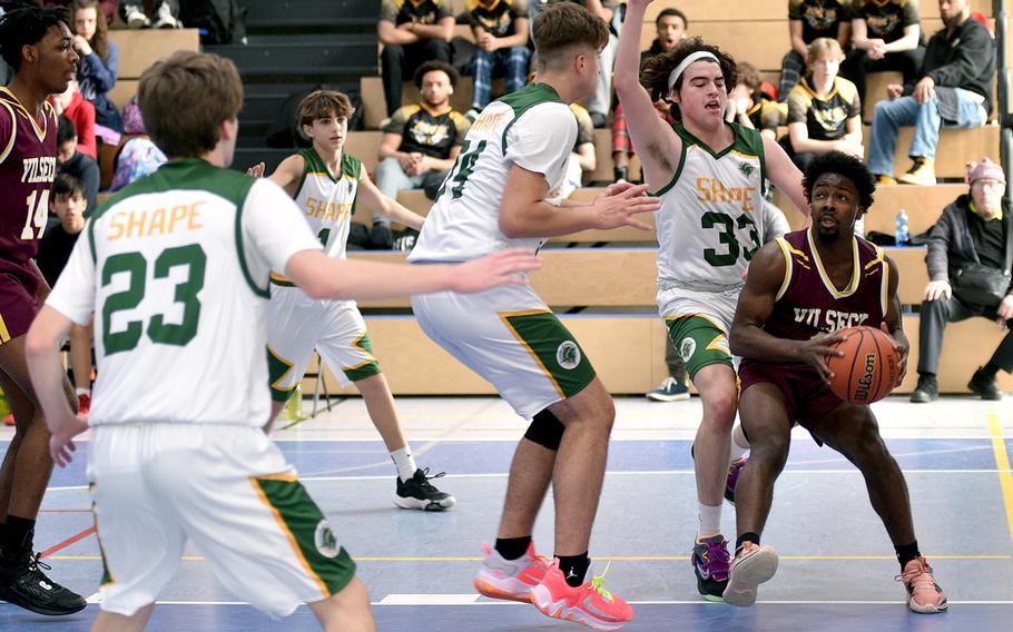 Vilseck's DeVaughn Terrell drives the baseline against SHAPE's Douglas Forbes, right, Thomas Tsoulas, center, during pool play of the Division I DODEA European Basketball Championships on Wednesday at Ramstein High School on Ramstein Air Base, Germany.