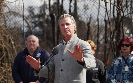 California Governor Gavin Newsom gestures as he speaks through a microphone.
