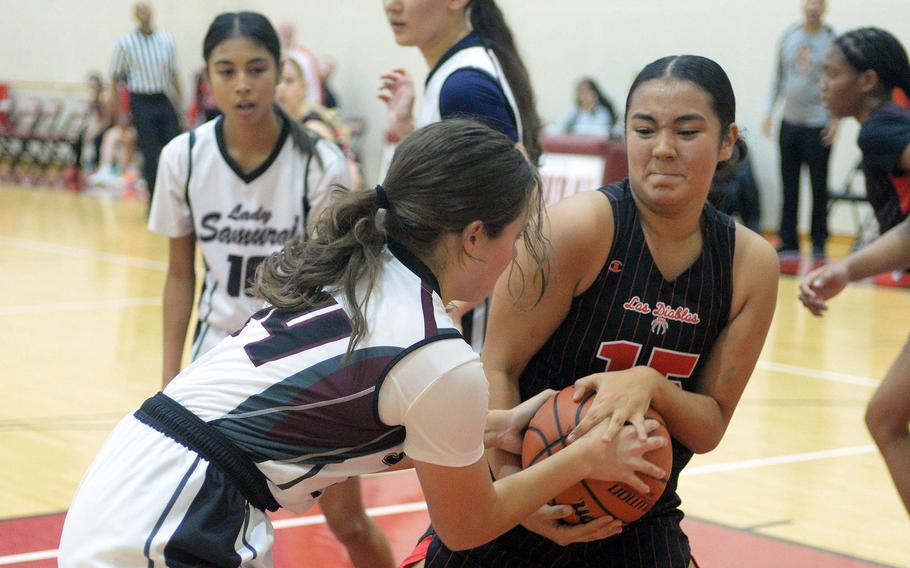 Matthew C. Perry's Cambria Villanueva and Nile C. Kinnick's Leona Turner play tug-of-war with the ball during Friday's DODEA-Japan girls basketball game. The Red Devils won 37-14.