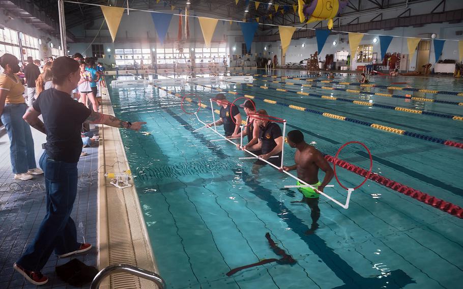 Volunteers from Naval Facilities Engineering Command and the Navy dive locker help out from inside the pool during the SeaPerch Challenge at Yokosuka Naval Base, Japan, Sunday, March 20, 2022.