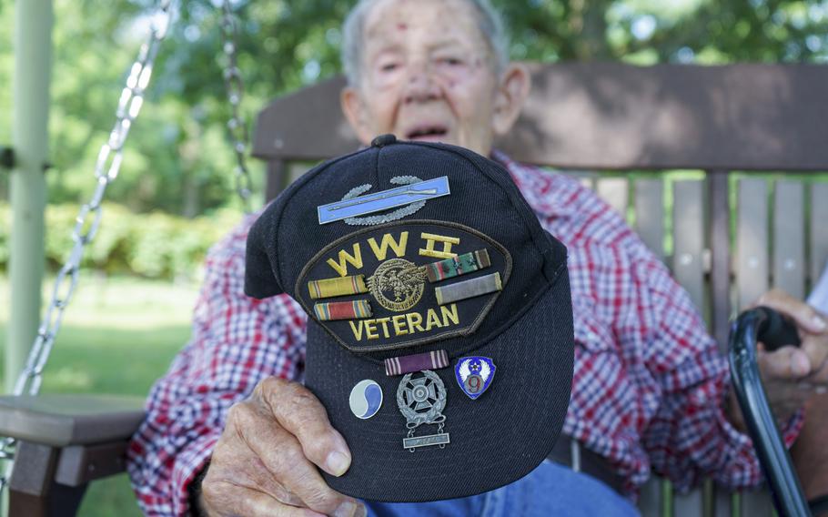 Beverly Salyards holds up his World War II veteran hat, adorned with several service ribbons and badges he earned during his time in the U.S. Army while talking about his experiences at Vietnam veteran Larry Ritchie's home in Rockingham County, Va. 