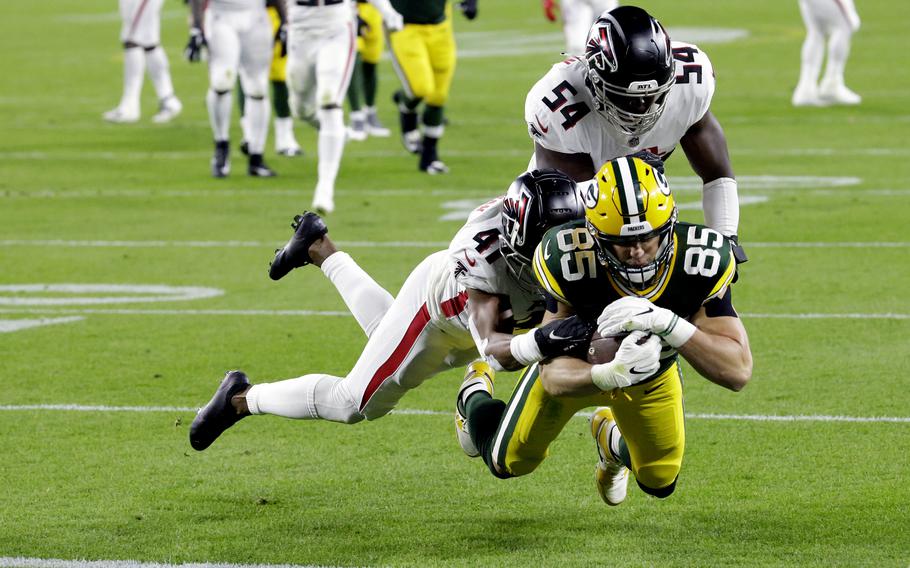 Green Bay Packers' Robert Tonyan (85) goes in for a touchdown as he is tackled by Atlanta Falcons' Sharrod Neasman (41) and Foye Oluokun (54) during the first half of an NFL football game, Monday, Oct. 5, 2020, in Green Bay, Wis. (AP Photo/Mike Roemer)