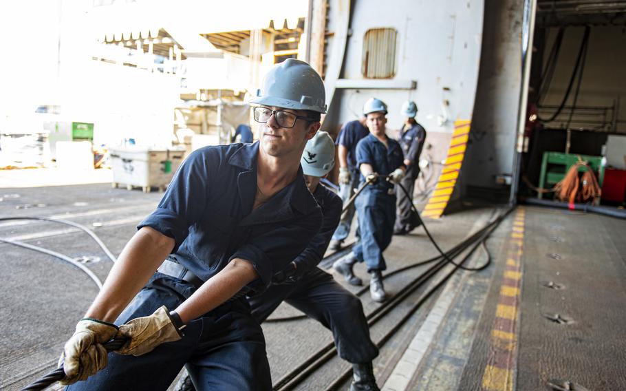 Crew members on the aircraft carrier USS Dwight D. Eisenhower hoist an elevator door cable during maintenance at the Norfolk Naval Shipyard, Va., Sept. 2, 2022.