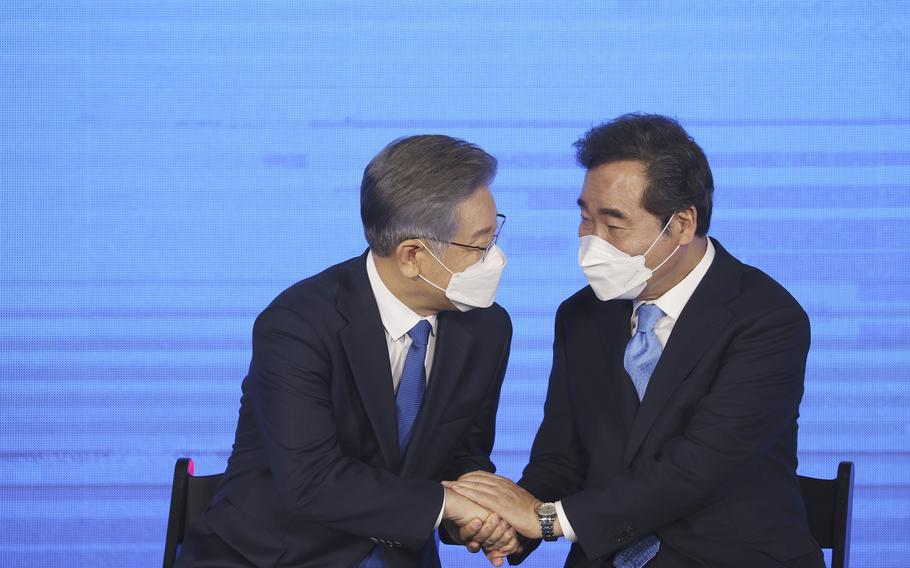 Gyeonggi Gov. Lee Jae-myung, left, elected as the ruling Democratic Party's candidate for next year's presidential election, shakes hands with former Prime Minister Lee Nak-yon after winning the party's final race to decide on the presidential candidate in Seoul, South Korea, Sunday, Oct. 10, 2021.