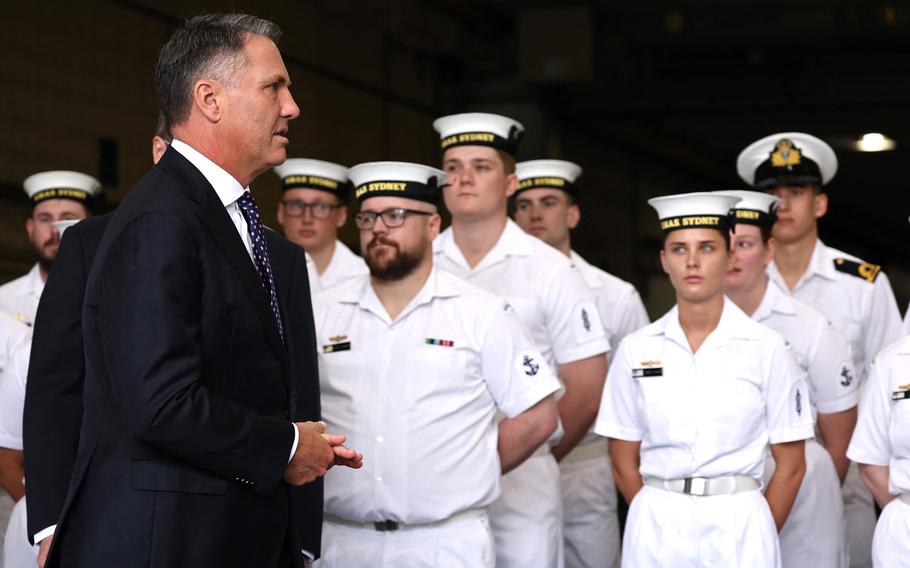 Australian Defense Minister Richard Marles walks past Royal Australian Navy sailors aboard the HMAS Canberra in Sydney on Feb. 20, 2024. 