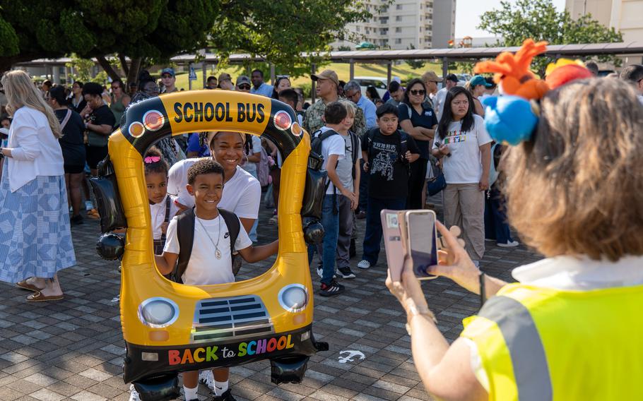 A family poses for a photograph behind a school bus-shaped frame.
