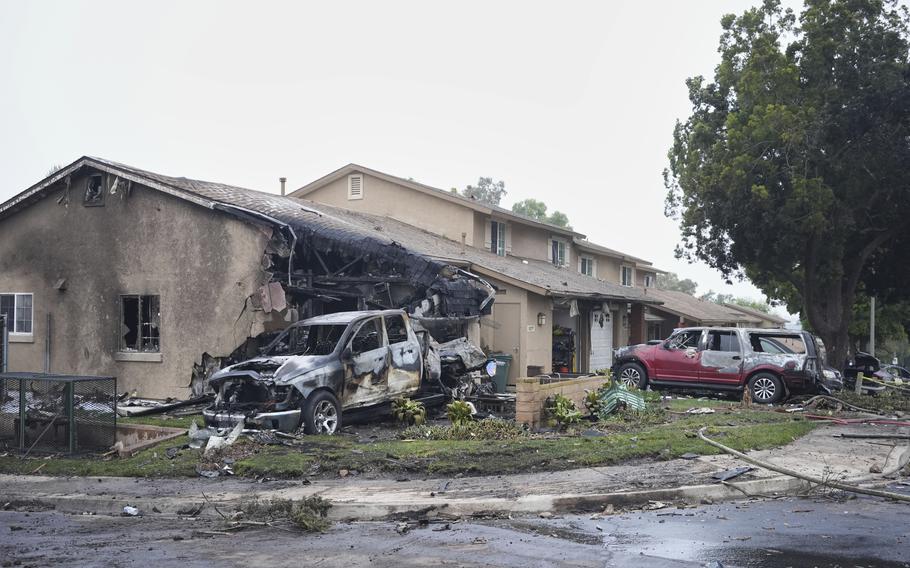 A house in a suburban neighborhood damaged with part of a wall blackened and another wall destroyed.
