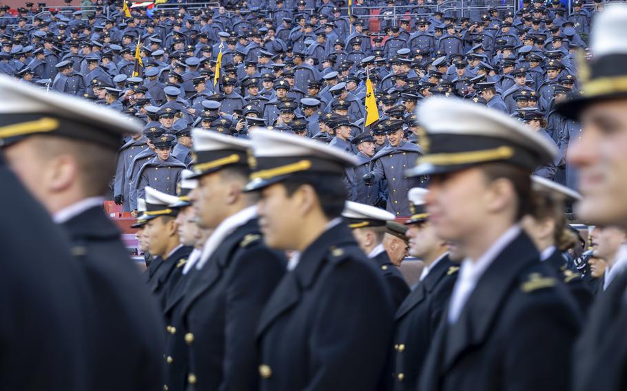 Army cadets from the stands watch the Navy midshipmen march onto the field.