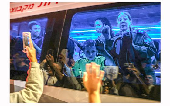 Gal Almog-Goldstein, 11, seen through left window, and his brother Tal, 9, seen through right window, stand in a bus transporting them to an army base in southern Israel after the Hamas militant group released them from the Gaza Strip on Nov. 26, 2023. 