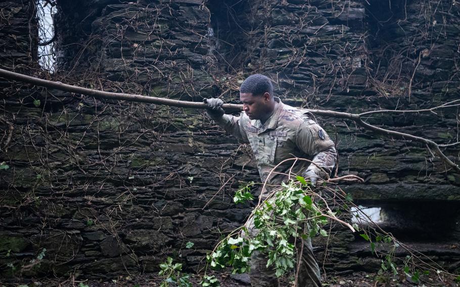Sgt. Lamar Richardson walks through smoky air, carrying a felled tree, as part of efforts to protect an old castle wall in St. Goar, Germany, on Feb. 23, 2023.