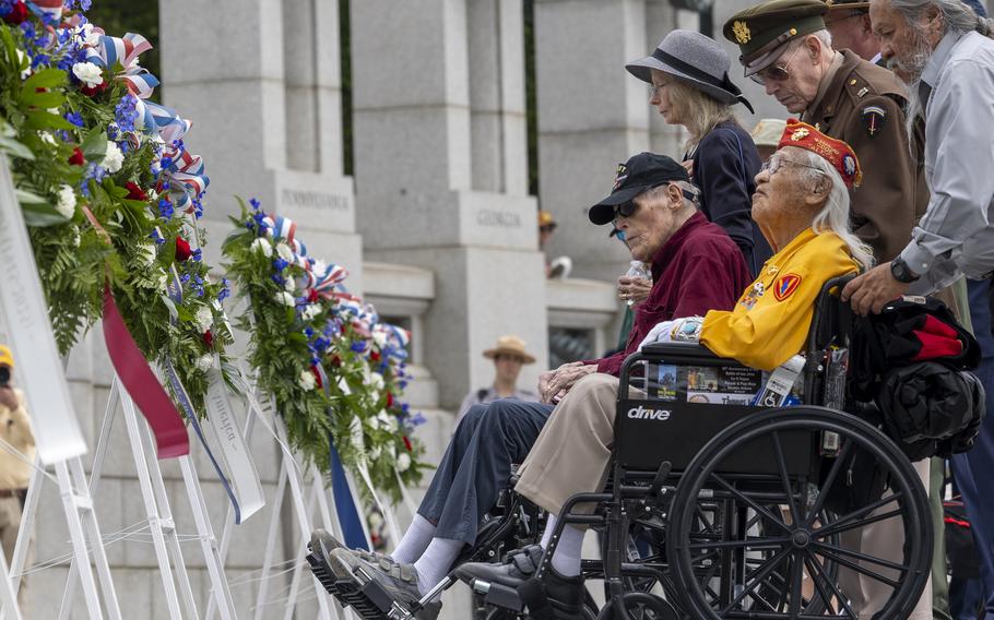 People standing in front of wreaths at a memorial.