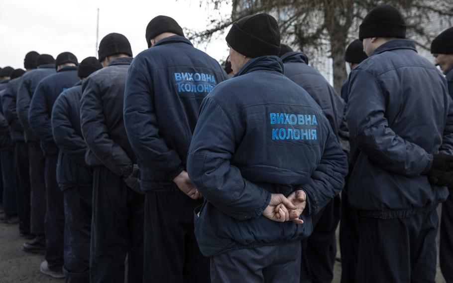 Russian prisoners of war captured by Ukrainian forces during the conflict stand with their hands held behind their backs as they walk slowly towards a building for lunch at a Ukrainian detention camp located in western Ukraine on Jan. 17, 2023.