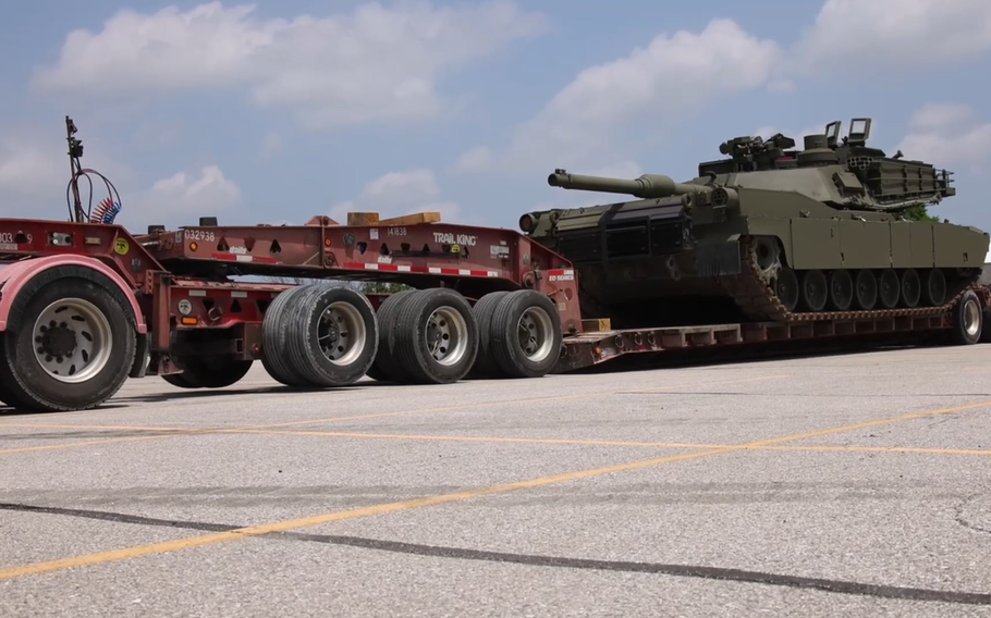 A tank being loaded onto a truck pallet. 