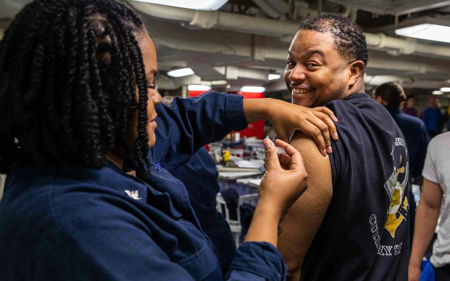 Petty Officer 2nd Class Chanel Friday, a hospital corpsman assigned to the aircraft carrier USS George H.W. Bush, vaccinates a sailor against COVID-19 on Dec. 12, 2022, while on the Adriatic Sea.