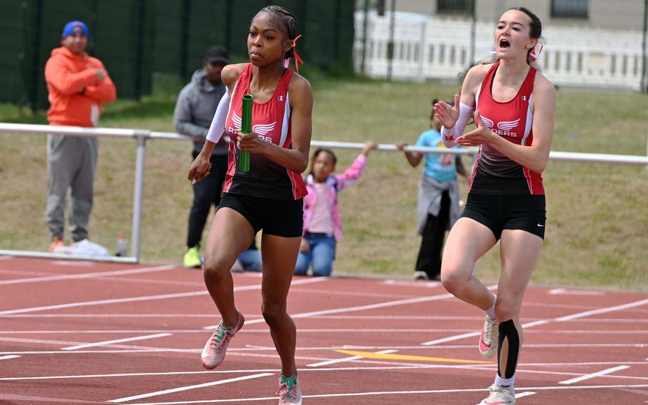 Kaiserslautern’s Lillian Griffin cheers on teammate Lellah Guhn after passing her the baton in the girls 4x100-meter relay at the 2025 DODEA-Europe track and field finals in Kaiserslautern, Germany. The pair, along with Trinity Seaberry and Kaelyn Ronnau, won the race in 49.72 second.