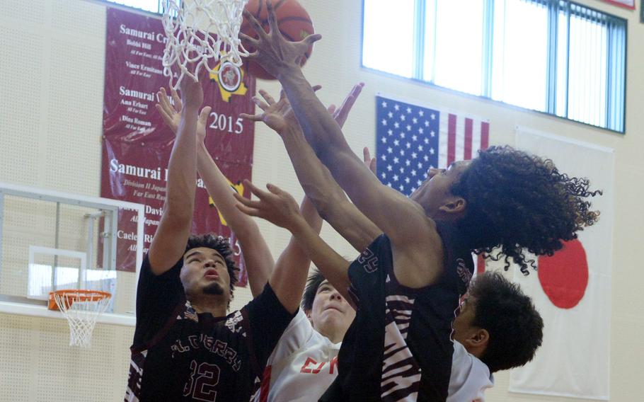 Matthew C. Perry's Roy Clayton III and Shion Fleming and E.J. King's Cameron Reinhart and Sean Bautista sky for a rebound during Saturday's DODEA-Japan boys basketball game. The Samurai won 48-39.