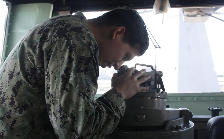 Petty Officer 2nd Class Adrian Ortiz practices taking a bearing on the starboard bridge wing of USS Bataan.