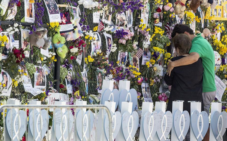 People mourn at the memorial wall for the victims of the Champlain Towers South collapse, in Surfside, Fla., on July 8, 2021.