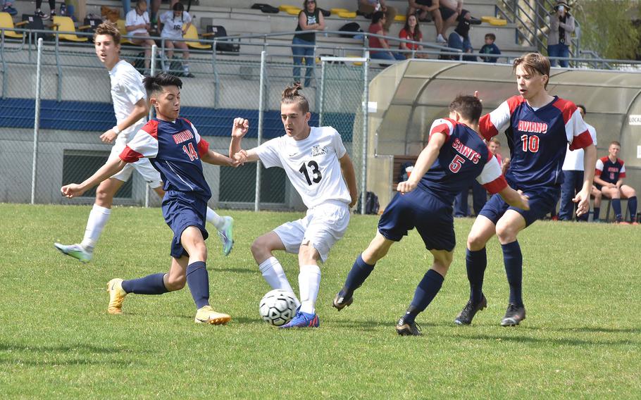 Aviano’s Keoni Andres, left, and Josh Barthold try to take the ball away from Naples’ Izen Hataburda in the Wildcats’ 3-2 victory over the Saints on Saturday, April 16, 2022 in Aviano, Italy.