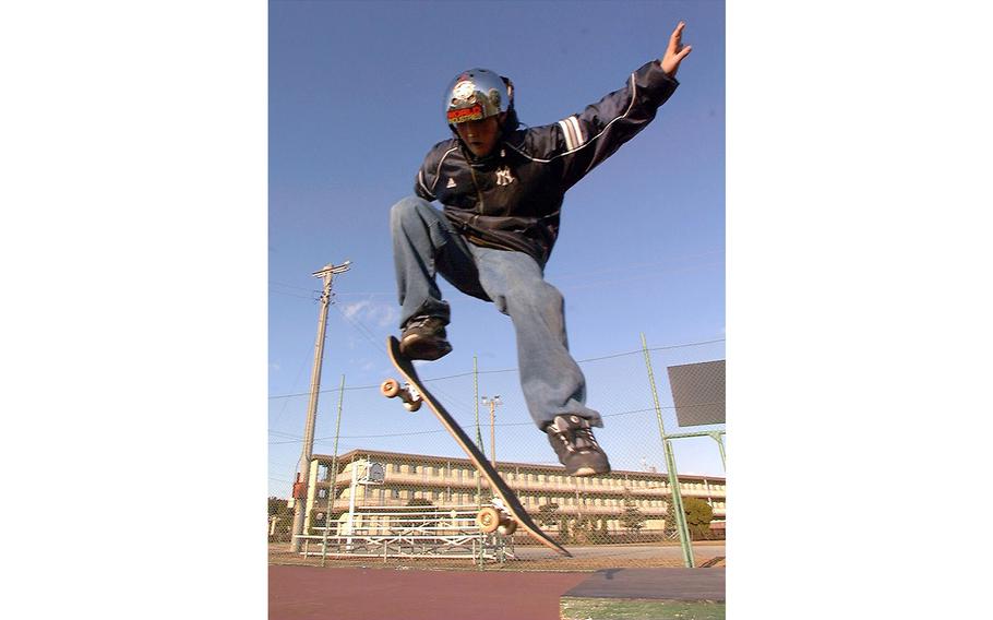 A vertical photo of a man in a helmet doing a stunt on a skateboard.