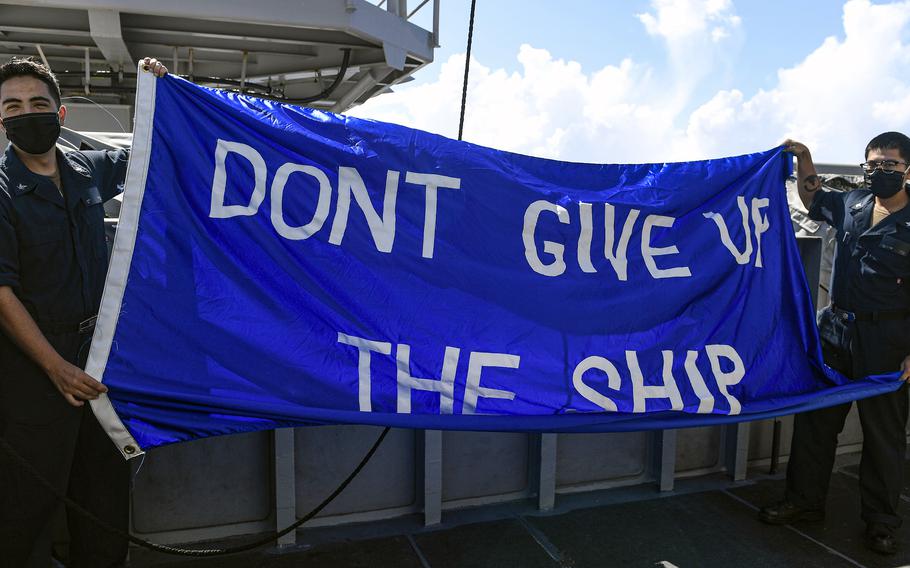 Sailors hold a “Don’t Give Up the Ship” flag aboard the aircraft carrier USS Theodore Roosevelt at Naval Base Guam, June 3, 2020.