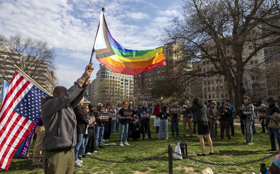 Protesters gathered in a park, with some of them waving flags.