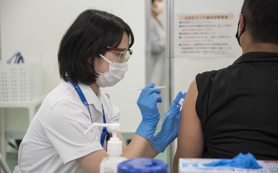 A medical worker with the Japan Ground Self-Defense Force injects a patient with the Moderna COVID-19 vaccine during a mass shot clinic in Otemachi, Tokyo, Wednesday, June 9, 2021. 