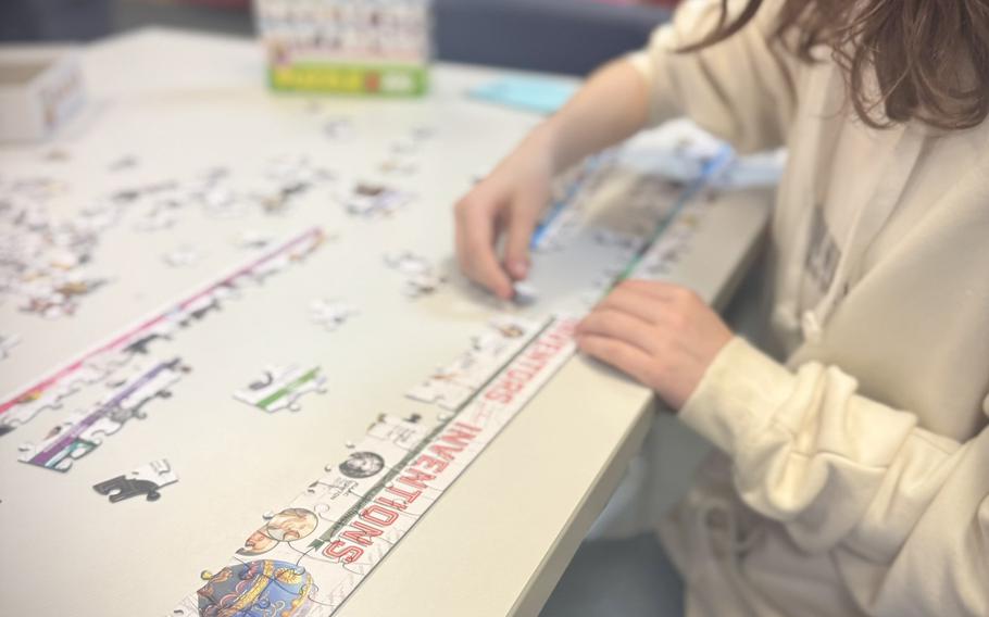 A middle schooler puts together a puzzle that reads “inventions” at the top.