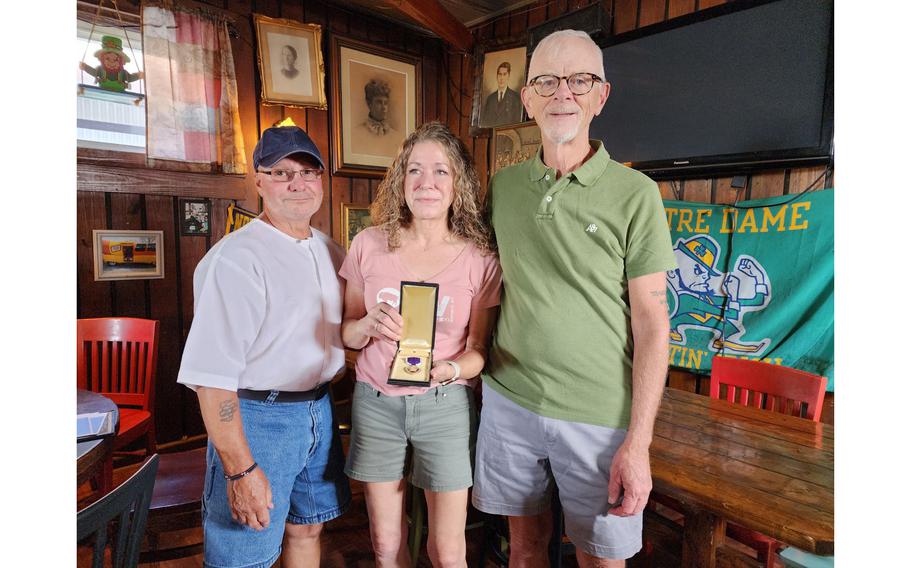 Jim Corbran, right, gives Robert Greiner’s Purple Heart medal to Greiner’s nephew, Kevin Greiner, and Kevin’s wife, Sandra, at Gene McCarthy’s historic First Ward tavern in Buffalo, N.Y., Thursday, Sept. 7, 2023.